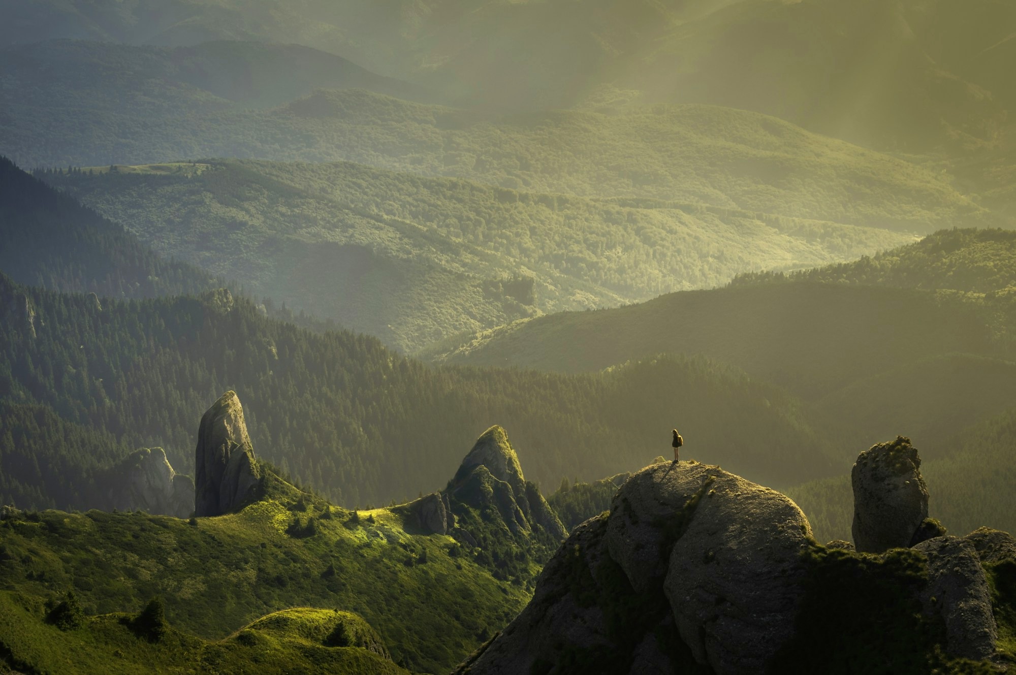 Mountain ridges lit by morning sun with rays through golden haze